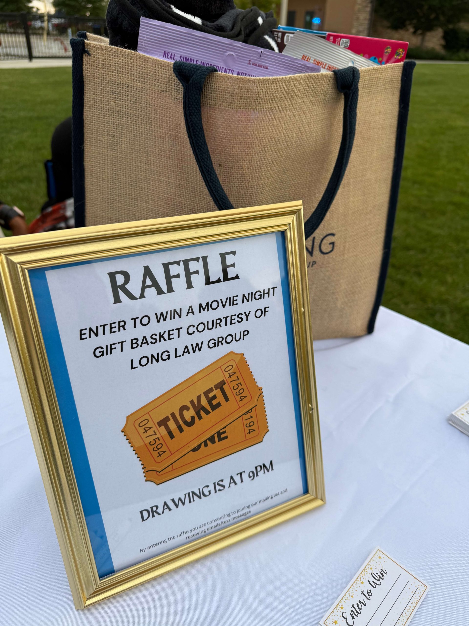 Long Law Group raffle sign for movie night gift basket prize drawing at 9PM with branded tote bag at community sponsorship booth